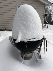 snow piled high on a Weber Kettle in Michigan